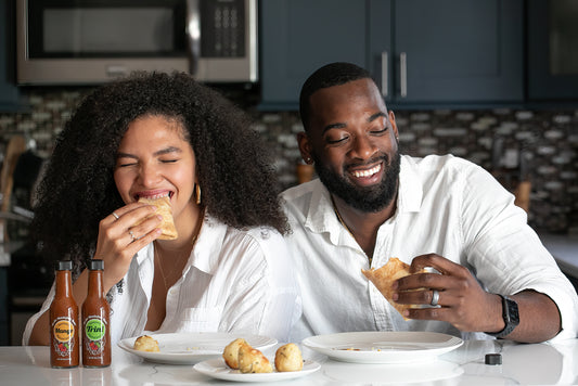 two people eating pizza with pepper sauce and laughing