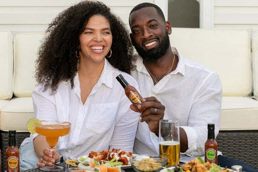 two people laughing with pepper sauce and food